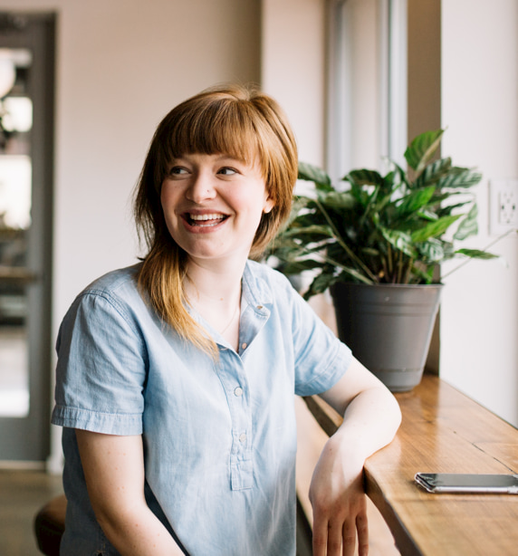 Lady in blue short-sleeve shirt smiling at someone off camera