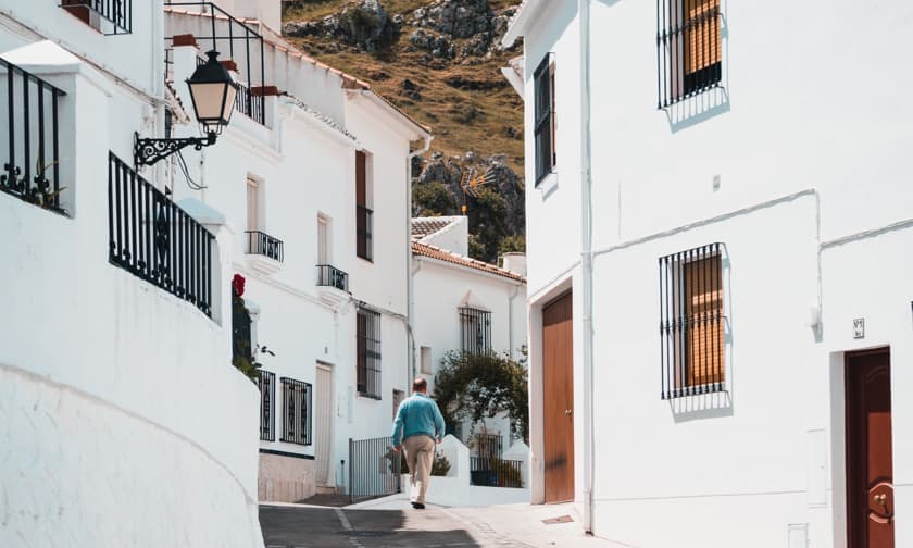 Man walks through sleepy European village with white-washed buildings